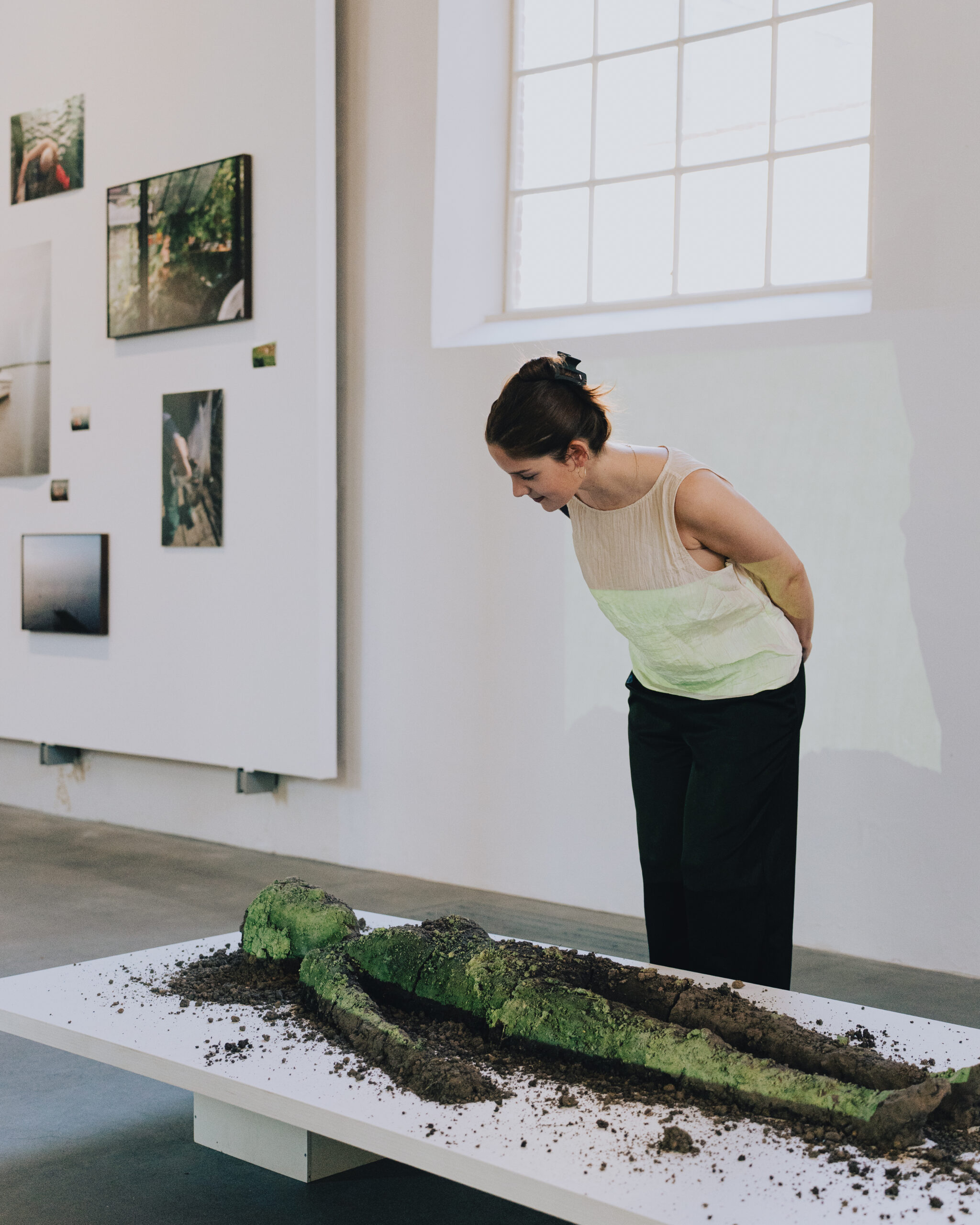 Woman looking at artwork, a Sculpture made of with PFAS polluted earth, an artwork about ecological fear, in the context of the pollution scandal of Chemours factory